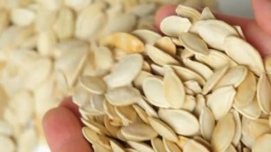 Bir avuç dolusu kavrulmuş balkabağı çekirdeği ellerinden dökülüyor, ağır çekimde..