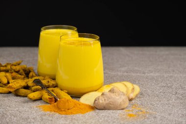 Altın süt, siyah gri arka planda iki kadehte zerdeçal içeren geleneksel bir Ayurvedik içeceği..