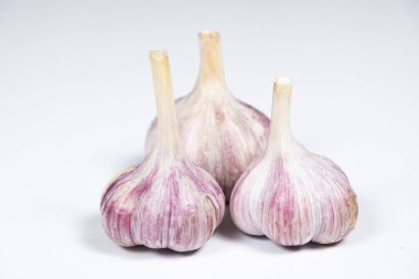 Beyaz bir arka planda soyulmamış taze sarımsak soğanı..