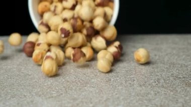 Gri taşlı arka planda soyulmuş fındık parçaları, yavaş çekim.