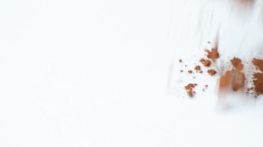 Beyaz arka plana dökülen kakao tozu, makro yavaş çekim