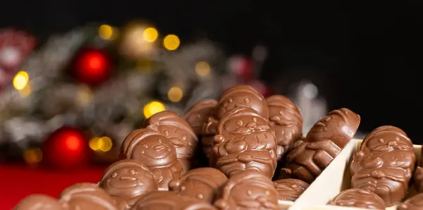 stock image Chocolates in the shape of Christmas figures on the background of a flashing garland.