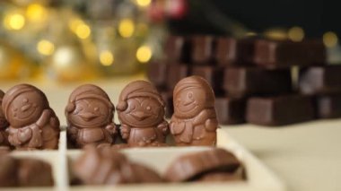 Parlayan bir çelengin arka planında Noel figürleri şeklinde çikolatalar..
