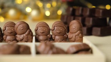 Parlayan bir çelengin arka planında Noel figürleri şeklinde çikolatalar..