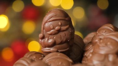 Parlayan bir çelengin arka planında Noel figürleri şeklinde çikolatalar..
