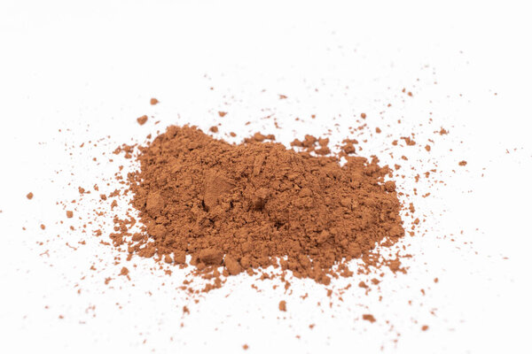 Какао порошок разбросан на белом фоне крупным планом.