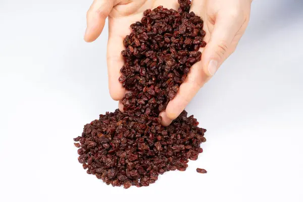 stock image Red dried barberry natural seasoning pouring out of human hands on white background.