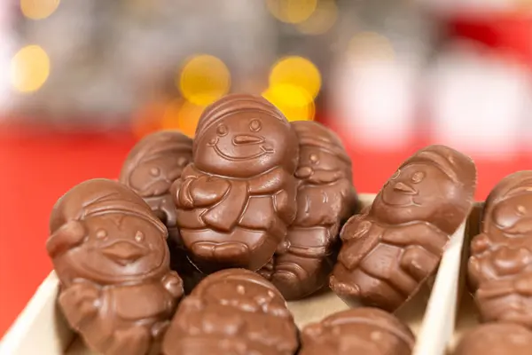 stock image Chocolates in the shape of Christmas figures on the background of a flashing garland.