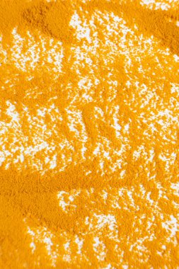 Beyaz arkaplan görünümüne dökülen zerdeçal tozunun soyut turuncu arkaplanı.