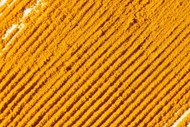 Beyaz arkaplan görünümüne dökülen zerdeçal tozunun soyut turuncu arkaplanı.