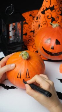 Hokkaido balkabağına göz, burun ve ağız çizer. Cadılar Bayramı için Jacks Feneri Oluşturuluyor.