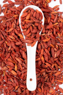 Kurutulmuş Goji üzümleri Lycium barbarlığı beyaz bir arka planda kaşık üst görünümü.