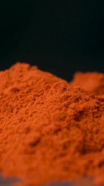 Baharatlı tütsülenmiş kırmızı biber dikey siyah arkaplana makro dökülüyor