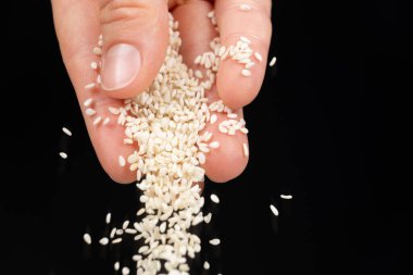 Siyah arkaplana beyaz susam tohumu dökülüyor.