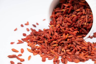 Kurutulmuş goji üzümleri beyaz arka planda bir tabaktan döküldü.