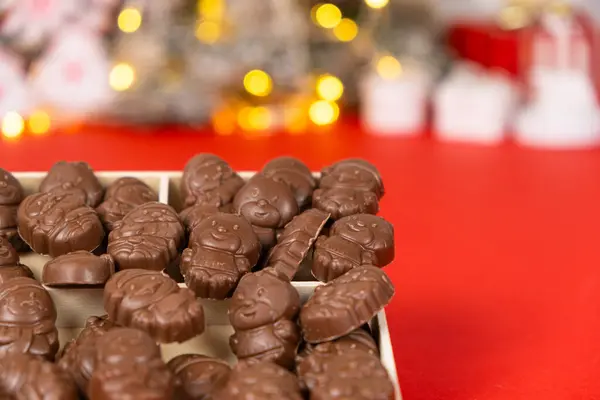 stock image Chocolates in the shape of Christmas figures in the wooden box on the red background.