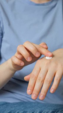 Bir kadın ellerine kozmetik kremi sürer. Dikey ağır çekim.