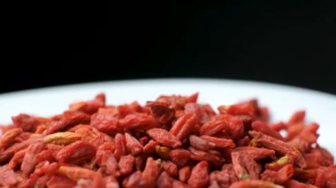 Siyah arka planda kurutulmuş goji üzümlerinin makro dönüşü.
