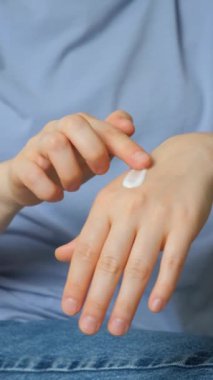 Bir kadın ellerine kozmetik kremi sürer. Cilt bakımı ve önleme