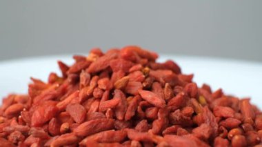 Gri arka planda kurutulmuş goji üzümlerinin makro dönüşü.