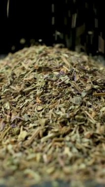 Fesleğen çeşnisi dökülüyor ve dönüyor, siyah arkaplan, dikey yavaş çekim.