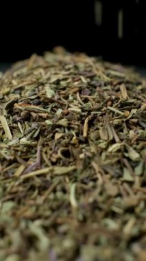 Fesleğen çeşnisi dökülüyor ve dönüyor, siyah arkaplan, dikey yavaş çekim.