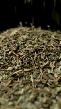 Fesleğen çeşnisi dökülüyor ve dönüyor, siyah arkaplan, dikey yavaş çekim.