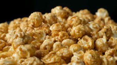 Karamelli patlamış mısırın dönüşü, siyah arkaplan.