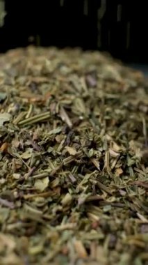 Fesleğen çeşnisi dökülüyor ve dönüyor, siyah arkaplan, dikey yavaş çekim.