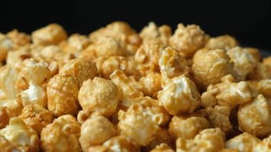 Karamelli patlamış mısırın yavaş dönüşü, siyah arkaplan.