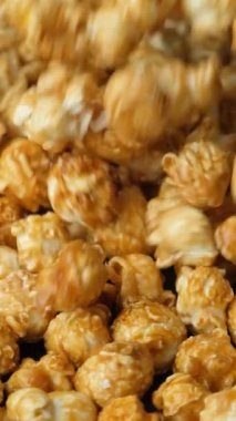 Karamelize edilmiş patlamış mısır dökülüyor ve dönüyor, dikey ağır çekimde.