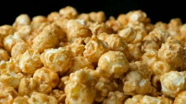 Karamelli patlamış mısırın yavaş dönüşü, siyah arkaplan.