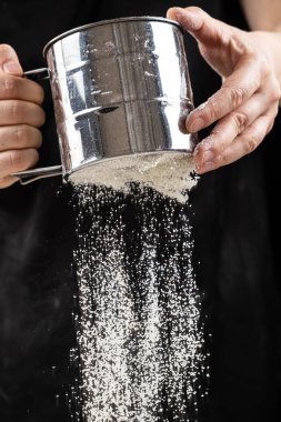 Aşçı buğday ununu bir metal süzgecinden geçirir.