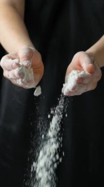 Aşçı ellerini unla çırpıyor, un sıçrıyor dikey ağır çekimde..