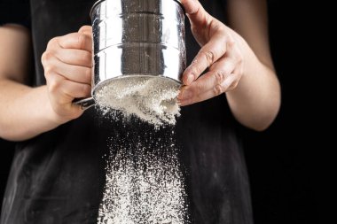 Aşçı buğday ununu bir metal süzgecinden geçirir.