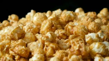 Karamelli patlamış mısırın yavaş dönüşü, siyah arkaplan.