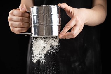 Aşçı buğday ununu bir metal süzgecinden geçirir..