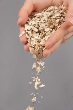 Eller gri bir zemine çiğ yulaf ezmesi döküyor.