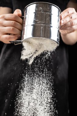 Aşçı buğday ununu bir metal süzgecinden geçirir..