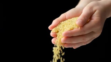 Eller çiğ bulgur gevreğini siyah arkaplan üzerine döküyor, metin için boşluk, yavaş çekim