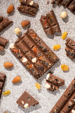 Arka planda fındık ve kuru üzümle kırılmış çikolata parçaları..