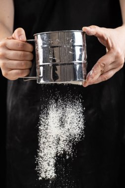 Aşçı buğday ununu bir metal süzgecinden geçirir.