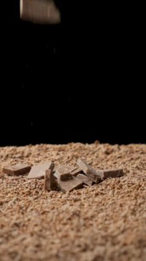 Çikolata parçacıkları çikolatanın içine düşüyor, dikey ağır çekimde..