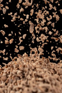 Parçalanmış doğal organik çikolata siyah arkaplan üzerine dökülüyor.