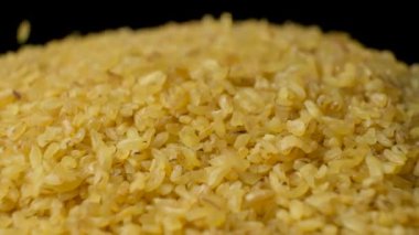 Pişmemiş bulgur buğday dökülmüş. Siyah arkaplanda makro yavaş çekim.
