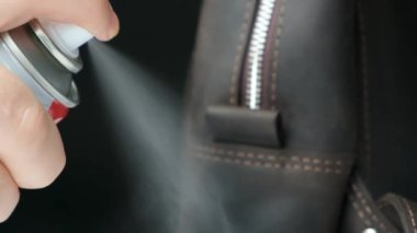 Spreyi deri bir sırt çantasına, aksesuar bakımına, ağır çekimde.