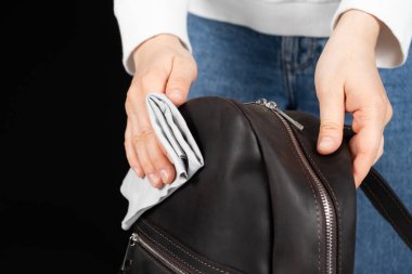 Deri bir sırt çantasının yüzeyini bir bezle temizliyorum. Deri aksesuarlarla ilgilenmek.