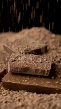 Çikolata rendelenmiş, sütlü çikolata parçaları, dikey ağır çekimde..