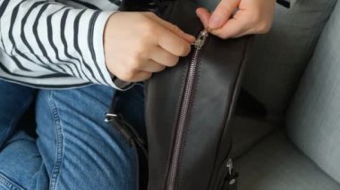 Deri bir sırt çantasındaki metal fermuarı açmak, yakın çekim, makro yavaş çekim.