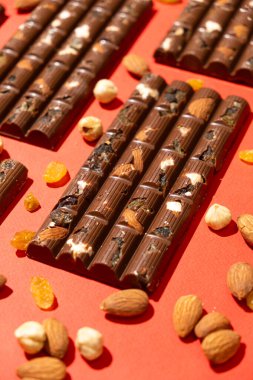 Kırmızı arka planda fındık ve kuru üzüm olan bir sürü çikolata..